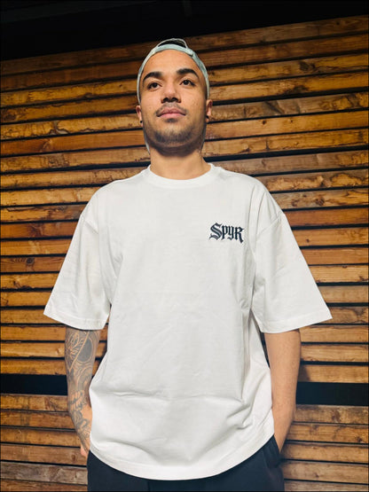 Man wearing a spyr white t-shirt  against a wooden wall